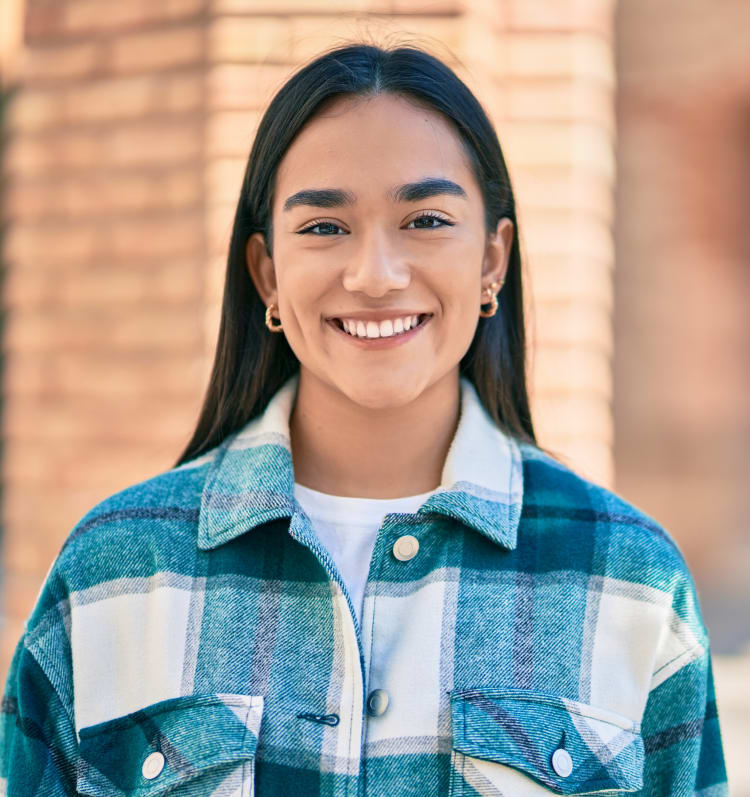 A young indigenous woman is smiling at the camera.