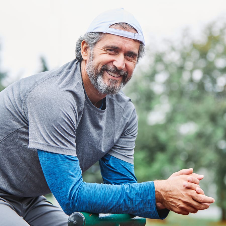 A man in a backwards cap takes a break outside and smiles at the camera.