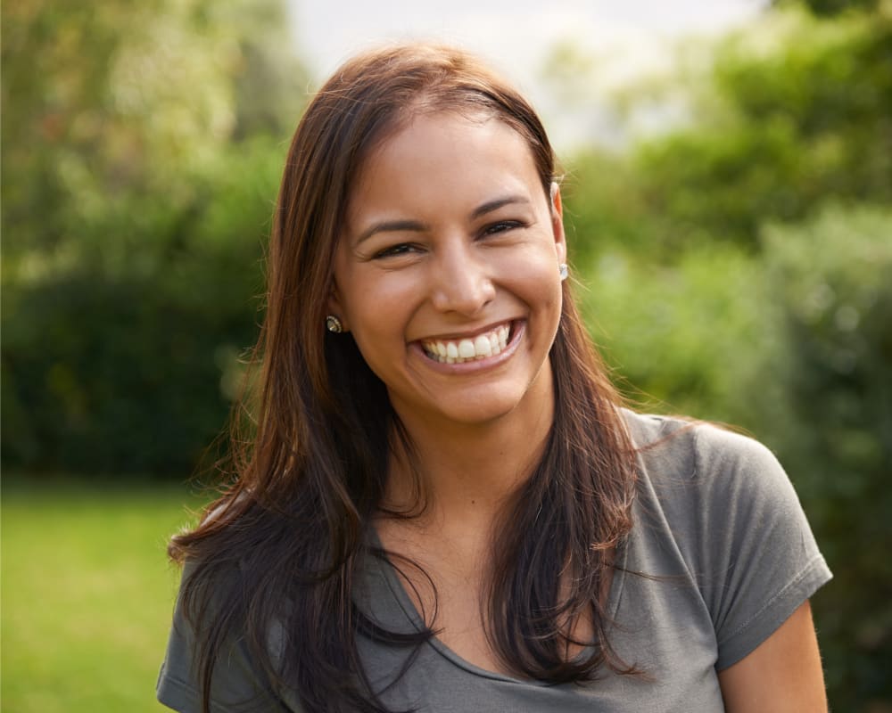 A young woman smiles while standing outside.